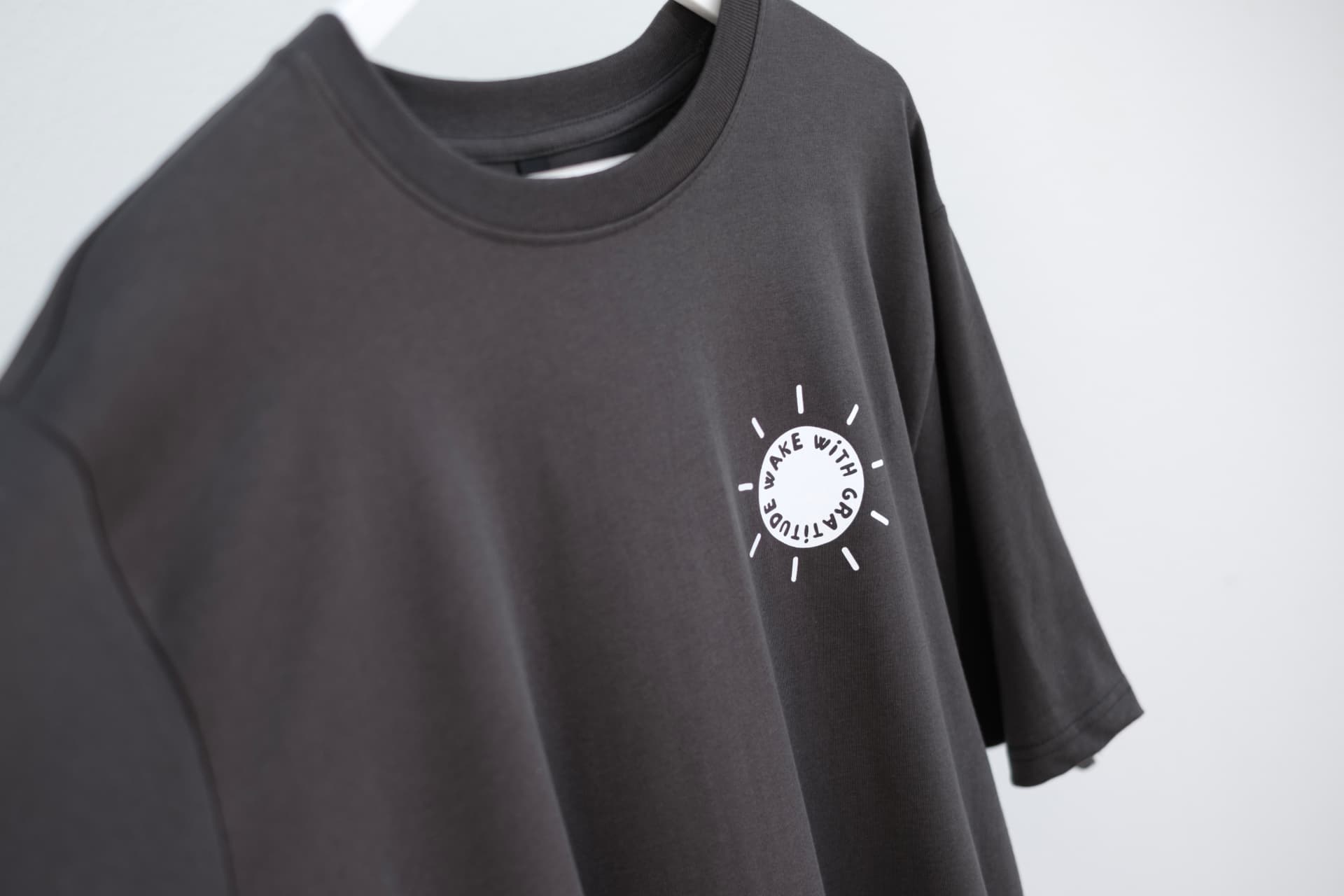 Washed black oversized Wake With Gratitude T-shirt hanging up